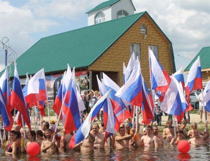 В Тюмени в День России офицер Росгвардии принял участие в массовом заплыве с флагами государства